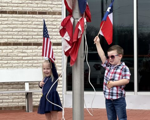 Marley Obusek and Hayes Hoglund proudly raise the American and Texas flags