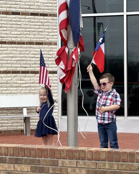Marley Obusek and Hayes Hoglund proudly raise the American and Texas flags