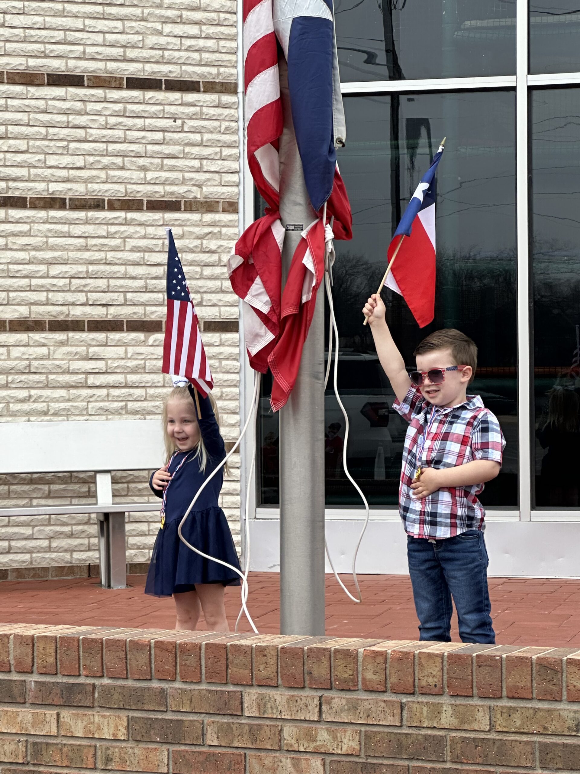 Marley Obusek and Hayes Hoglund proudly raise the American and Texas flags