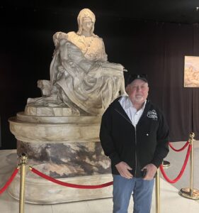 Founder of the Sistine Chapel Experience, Penn Parrish, in front of a reproduction of The Pietà, a Carrara marble sculpture depicting the Virgin Mary holding the body of Jesus by Michelangelo Buonarroti