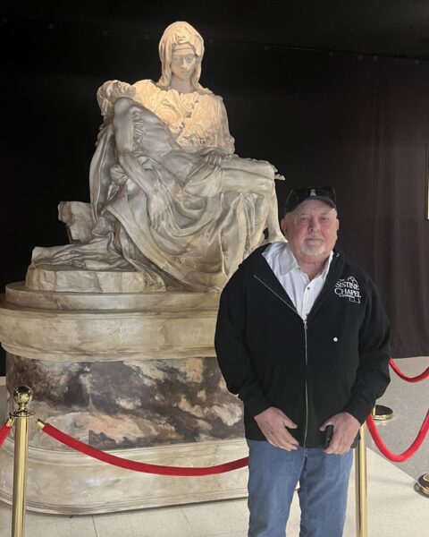 Founder of the Sistine Chapel Experience, Penn Parrish, in front of a reproduction of The Pietà, a Carrara marble sculpture depicting the Virgin Mary holding the body of Jesus by Michelangelo Buonarroti