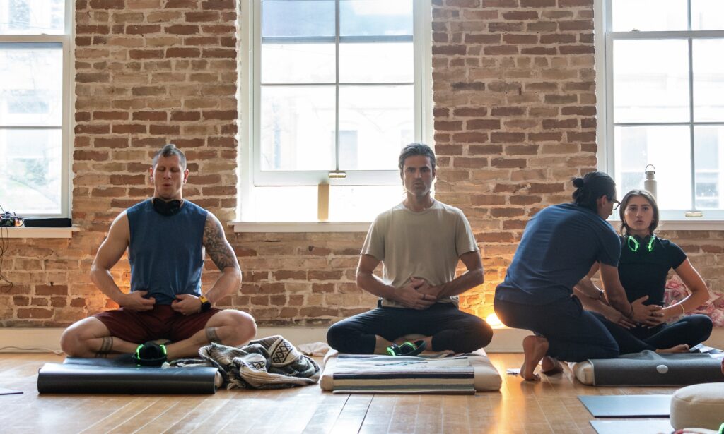 David Forrette, Jason Horner, and JJ Ruescas offering instruction to Alexa Moro during an Advanced Breathwork Journey at hŌM Yoga Studio