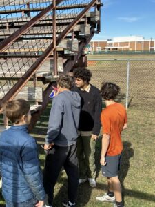 Rohan Sherwood Sharma (black sweatshirt) speaking to his work team about the repair of wooden bleachers at the South Austin Optimist Little League baseball field