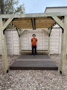 Leo Matney standing under the new pergola and seating he designed and constructed at Capitol School of Austin