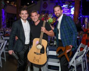 Dr. Ross Blagg, Dr. Mahlon Kerr with his signed Willie Nelson Guitar, and Jordan Staples