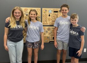 Cousins Brooklynn Pritchard, Dupree Jackson, Sawyer Jackson, and Kanin Pritchard In front of a Sensory Board at Embrace Ministry at Austin Ridge